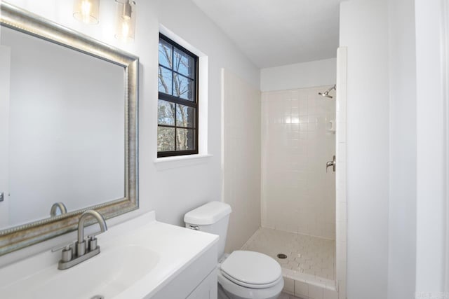 bathroom featuring vanity, toilet, and a tile shower