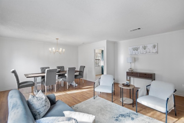 living room with crown molding, hardwood / wood-style floors, a textured ceiling, and an inviting chandelier