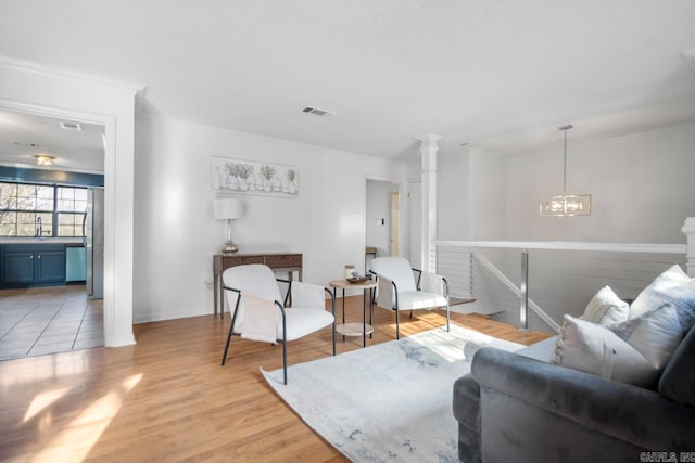 living room with a notable chandelier, light wood-type flooring, and ornamental molding