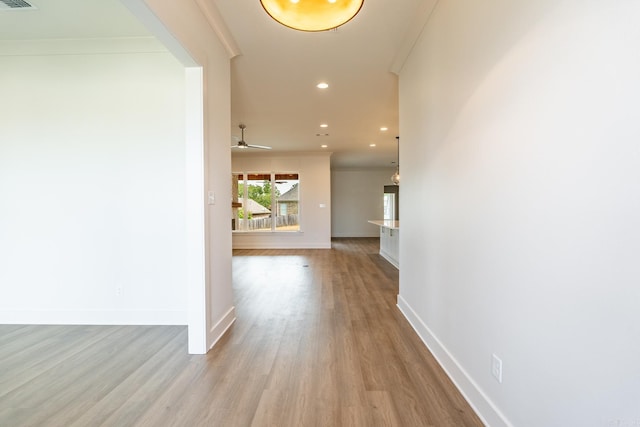 corridor featuring light wood-type flooring and crown molding