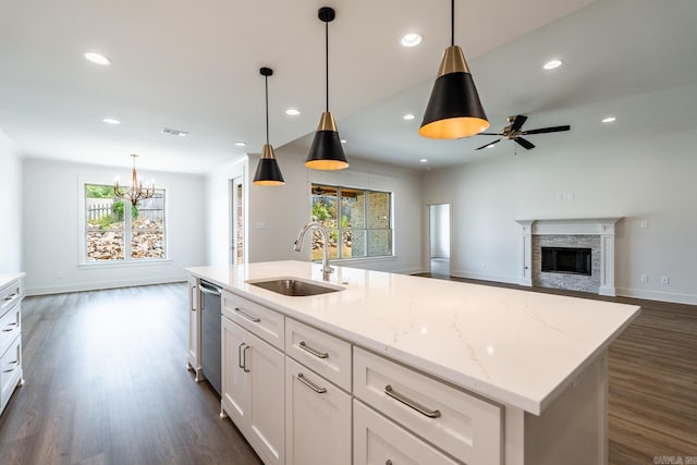 kitchen with a kitchen island with sink, sink, pendant lighting, and ceiling fan with notable chandelier