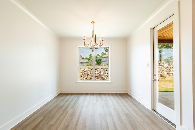 empty room with a healthy amount of sunlight, light hardwood / wood-style flooring, crown molding, and a notable chandelier