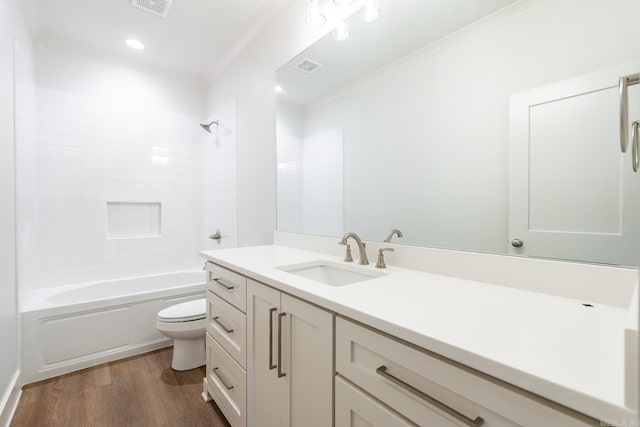 full bathroom with tub / shower combination, vanity, crown molding, wood-type flooring, and toilet