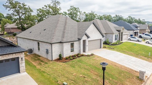 view of front of property featuring a front lawn, a garage, and central AC