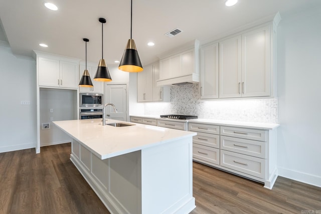 kitchen with white cabinets, pendant lighting, stainless steel appliances, and an island with sink