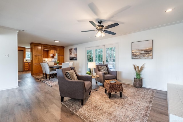 living room featuring hardwood / wood-style flooring, ceiling fan, and ornamental molding