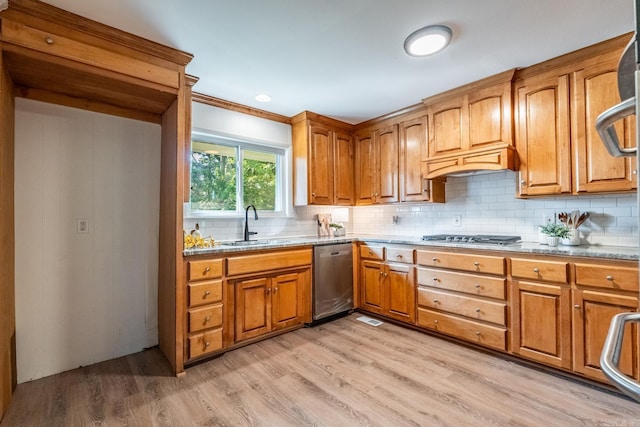 kitchen with decorative backsplash, light stone counters, stainless steel appliances, sink, and light hardwood / wood-style floors