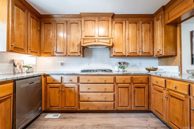 kitchen featuring premium range hood, tasteful backsplash, light hardwood / wood-style floors, light stone counters, and stainless steel appliances