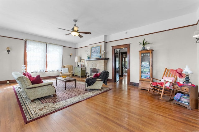 living room featuring ceiling fan, light hardwood / wood-style flooring, and a brick fireplace