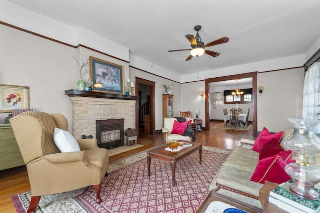 living room featuring a fireplace, hardwood / wood-style floors, and ceiling fan with notable chandelier