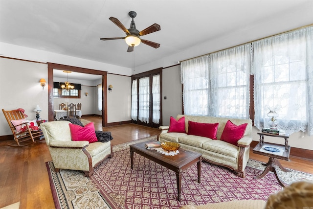 living room with hardwood / wood-style flooring, ceiling fan with notable chandelier, and a healthy amount of sunlight