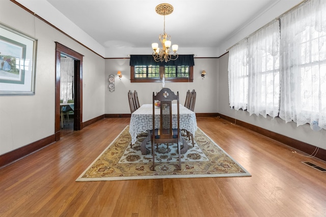 dining area featuring hardwood / wood-style floors and an inviting chandelier