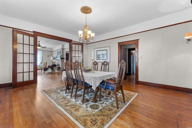 dining room featuring hardwood / wood-style flooring, ceiling fan with notable chandelier, and french doors