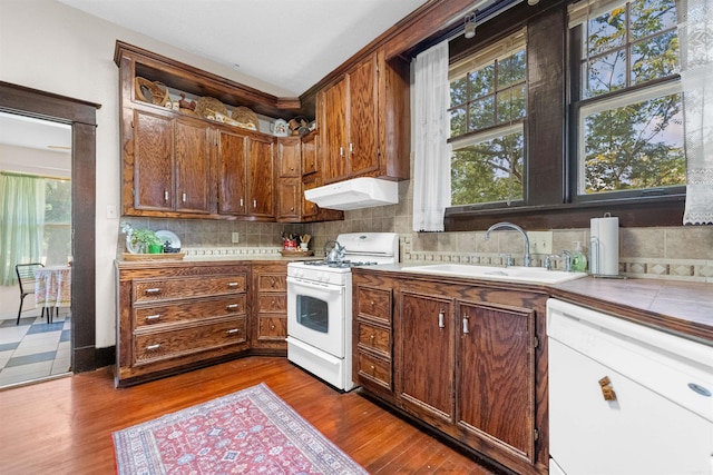 kitchen featuring decorative backsplash, white appliances, plenty of natural light, and sink