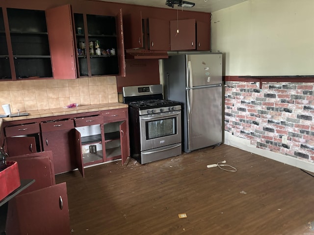 kitchen with appliances with stainless steel finishes, dark hardwood / wood-style flooring, and backsplash