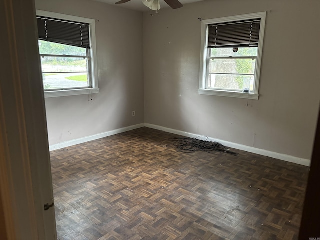 unfurnished room with dark parquet flooring and ceiling fan