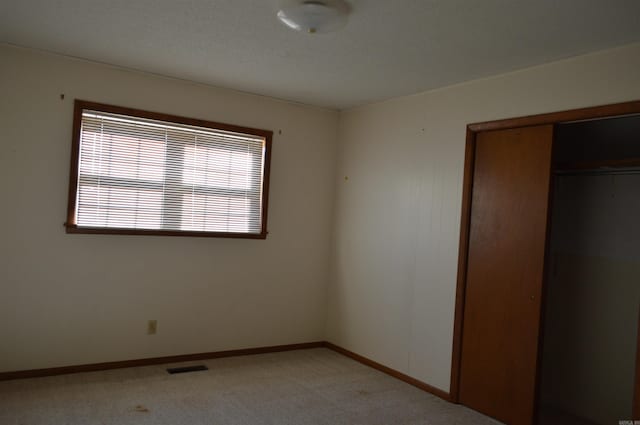 unfurnished bedroom featuring a closet and light colored carpet