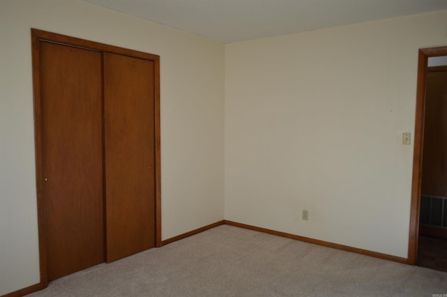 unfurnished bedroom with light colored carpet and a closet