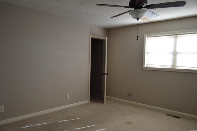 unfurnished room with ceiling fan, light colored carpet, and a textured ceiling