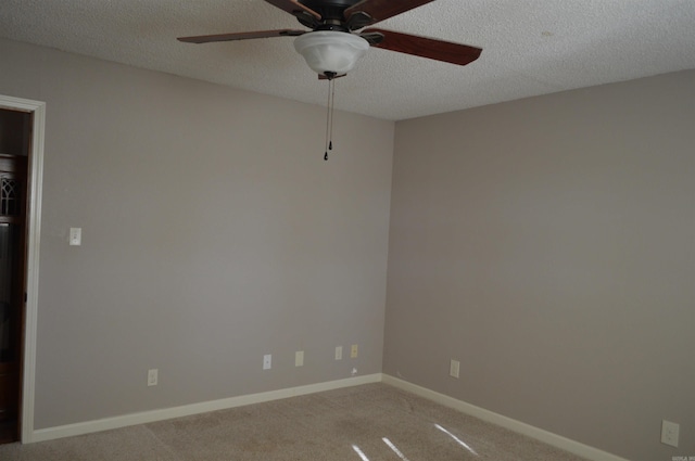 empty room with ceiling fan, light colored carpet, and a textured ceiling