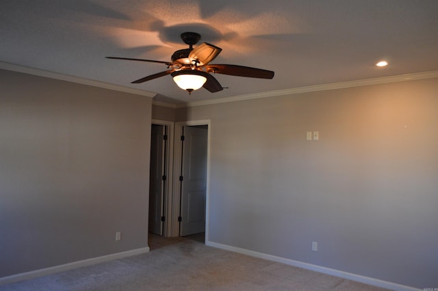 carpeted spare room featuring ceiling fan and ornamental molding