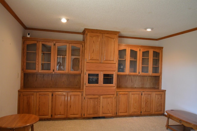 kitchen featuring a textured ceiling, crown molding, and light carpet