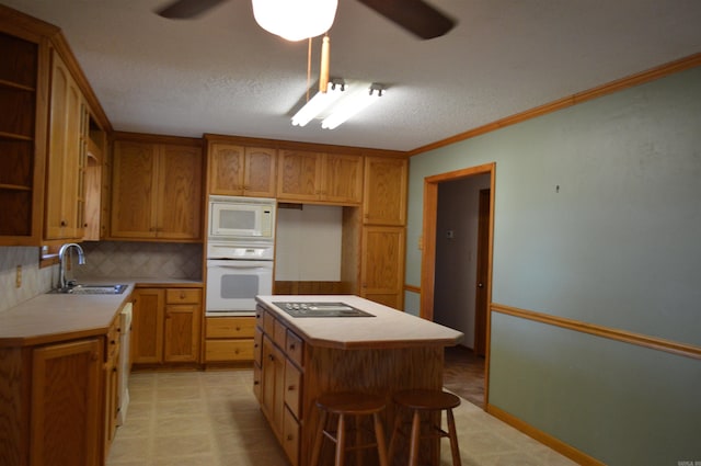 kitchen with backsplash, white appliances, crown molding, sink, and a kitchen island