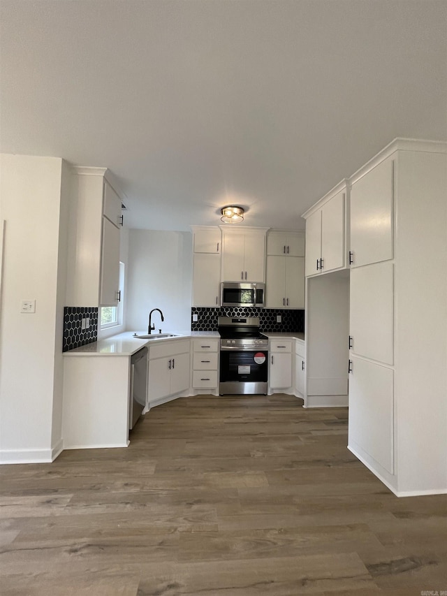 kitchen with stainless steel appliances, white cabinetry, hardwood / wood-style flooring, and sink