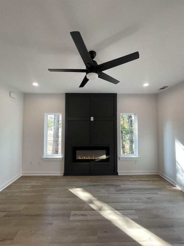 unfurnished living room featuring a wealth of natural light, a fireplace, ceiling fan, and light hardwood / wood-style flooring