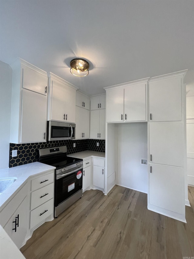 kitchen featuring decorative backsplash, light hardwood / wood-style flooring, white cabinets, and appliances with stainless steel finishes