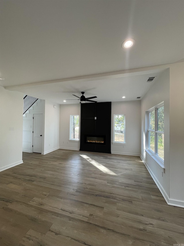 unfurnished living room with a fireplace, wood-type flooring, and a healthy amount of sunlight