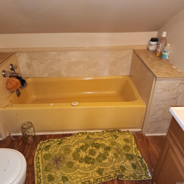 bathroom featuring hardwood / wood-style floors, a washtub, toilet, and vanity