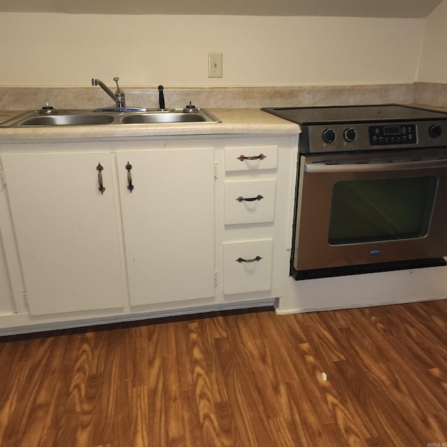 kitchen with stove, white cabinetry, and sink