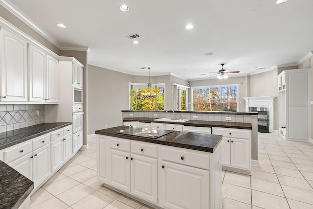 kitchen featuring white cabinets, oven, a kitchen island, and tasteful backsplash