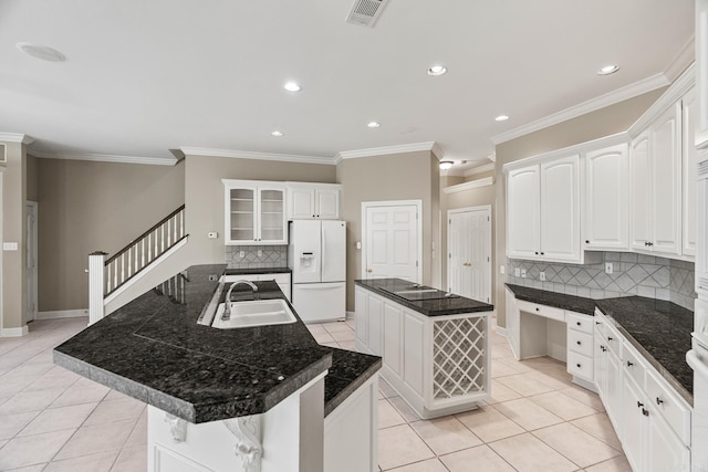 kitchen with backsplash, sink, white refrigerator with ice dispenser, white cabinets, and a center island