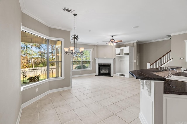 kitchen with crown molding, sink, light tile patterned floors, and decorative light fixtures