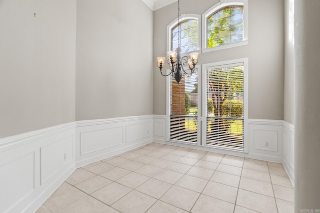 unfurnished dining area with light tile patterned floors, a chandelier, and ornamental molding