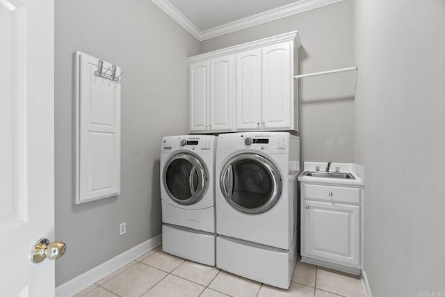 laundry room featuring cabinets, ornamental molding, sink, light tile patterned floors, and washing machine and dryer