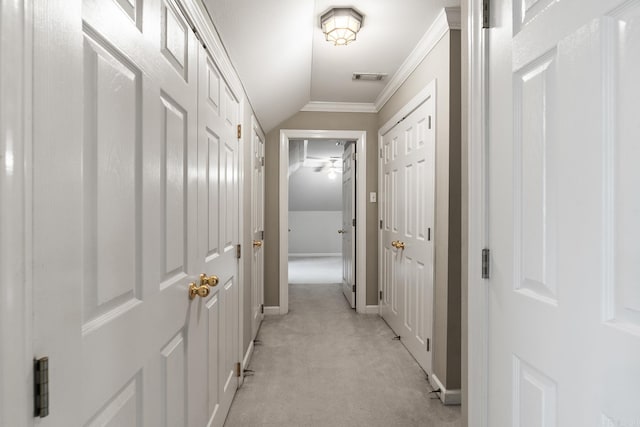 hallway with lofted ceiling, ornamental molding, and light carpet