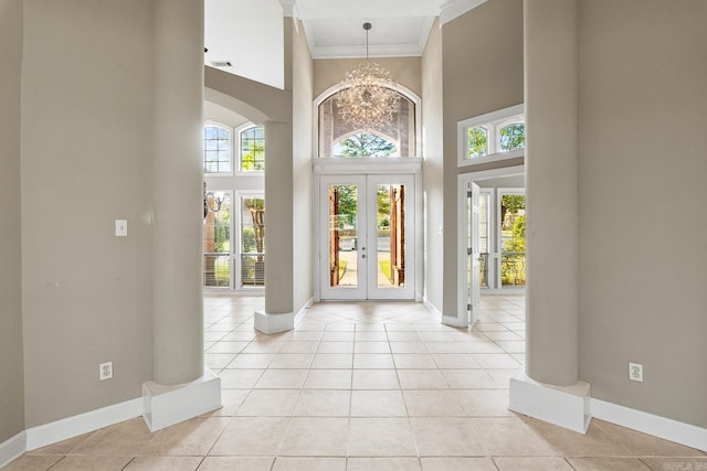 foyer entrance featuring french doors, a high ceiling, a chandelier, light tile patterned floors, and ornamental molding