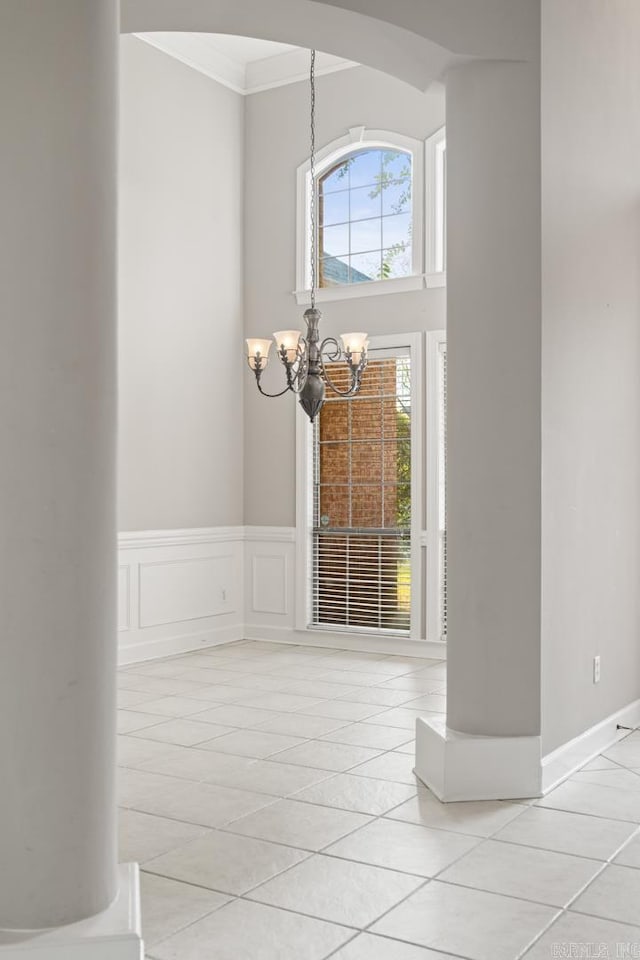 tiled entrance foyer featuring an inviting chandelier and ornamental molding