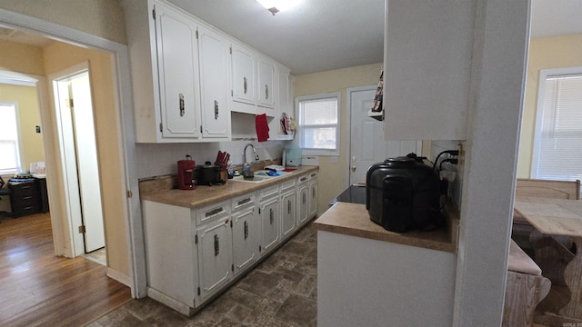 kitchen with decorative backsplash, white cabinetry, and sink