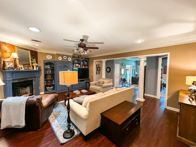 living room featuring decorative columns, ceiling fan, dark wood-type flooring, and ornamental molding