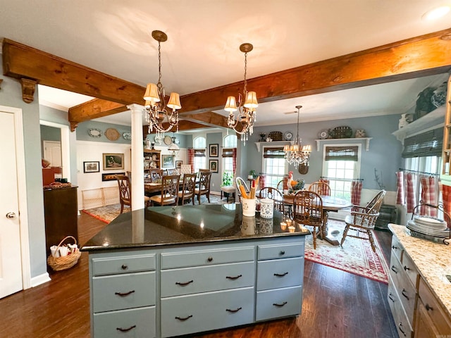 kitchen featuring a center island, dark stone counters, dark hardwood / wood-style floors, decorative light fixtures, and decorative columns