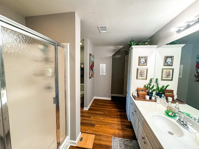 bathroom with wood-type flooring, vanity, toilet, and walk in shower