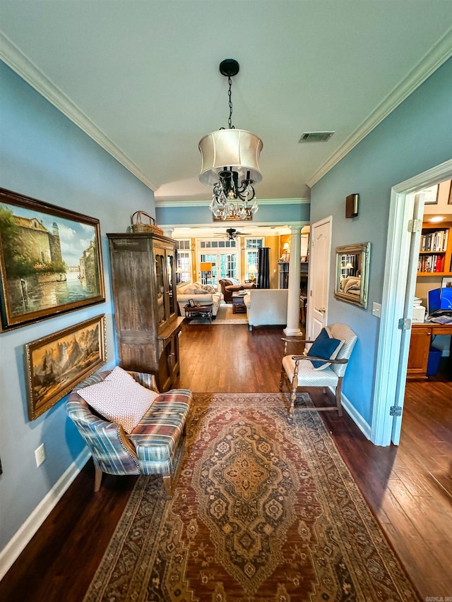 interior space with decorative columns, a chandelier, dark wood-type flooring, and ornamental molding