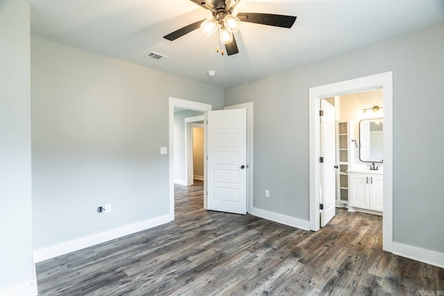 unfurnished bedroom featuring connected bathroom, ceiling fan, dark wood-type flooring, and sink