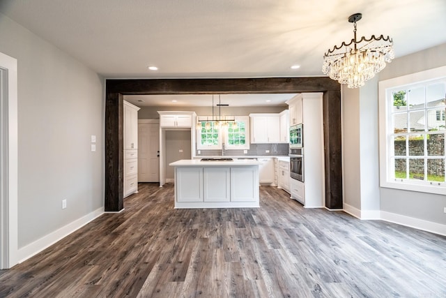 kitchen with a center island, white cabinets, stainless steel appliances, and decorative light fixtures