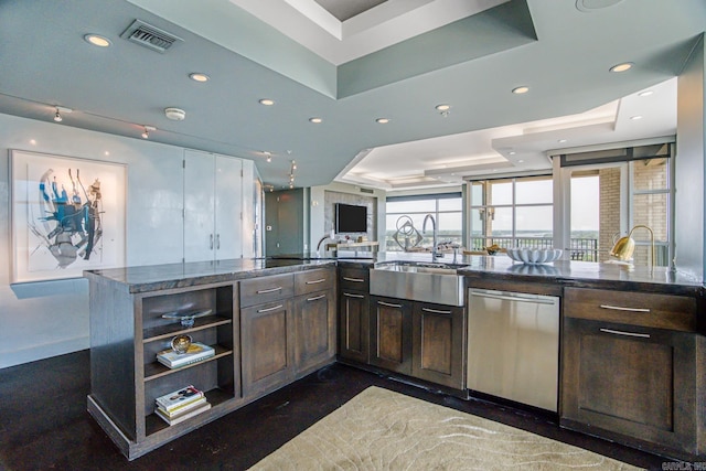 kitchen featuring dark brown cabinetry, sink, a raised ceiling, stainless steel dishwasher, and dark stone counters