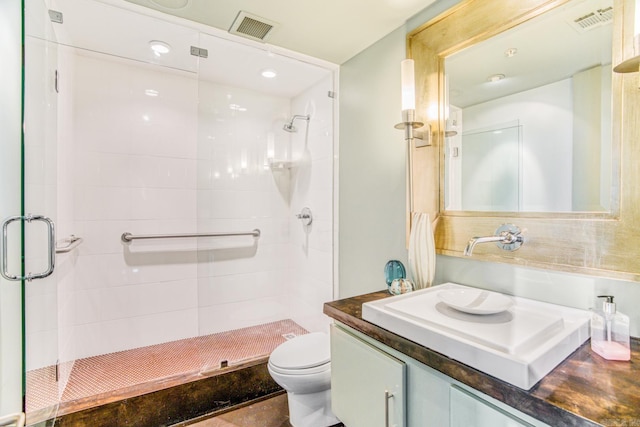 bathroom with vanity, toilet, and a shower with door